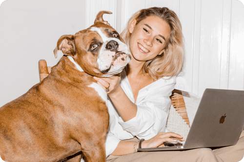 Blonde Frau sitzt mit einer braunen Bulldogge vor einem Macbook